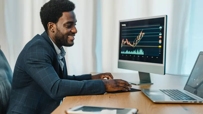 Professional marketing expert reviewing data on computer while smiling at his office.