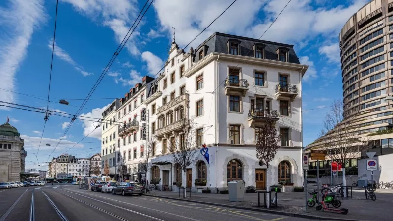 Hotel exterior of the Hotel Gaia Basel with cars, bicycles, and a tram in the foreground.