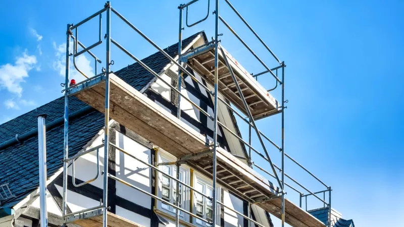 Scaffolding in front of exterior of hotel undergoing renovations on a clear blue sky day.