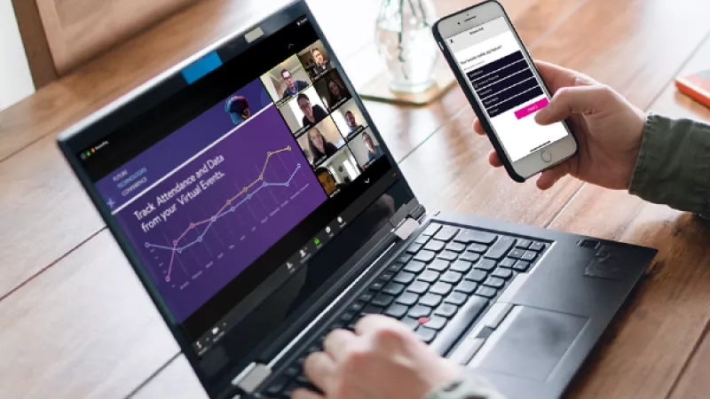 Person using laptop and mobile app to track attendance and data from virtual events.