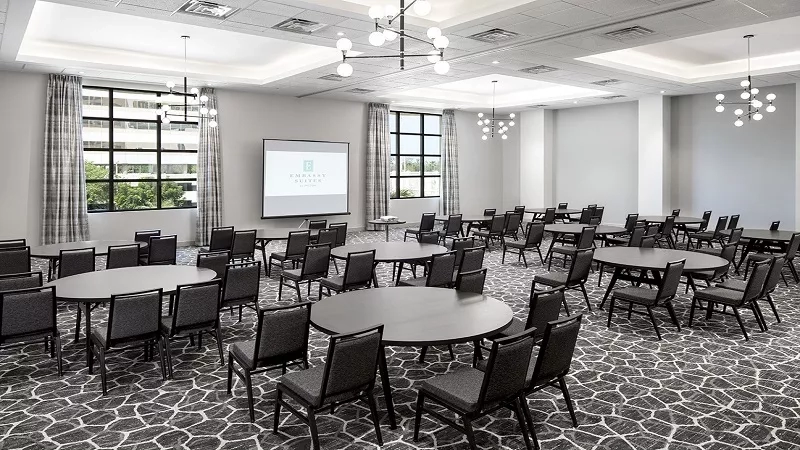 Meeting room at Embassy Suites by Hilton Tampa Westshore with round tables and a large screen.