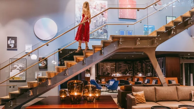 A woman is walking down a glass staircase at Andaz Munich Schwabinger Tor, a Hyatt Hotel.