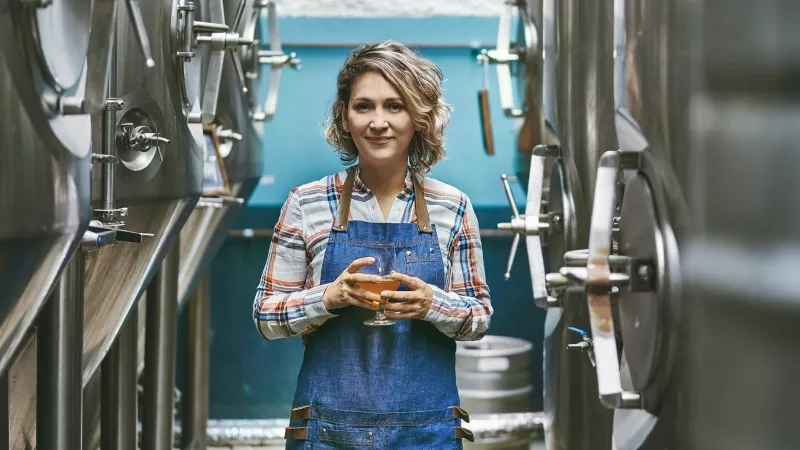 Woman holding craft beer in brewery for brewery marketing and advertising campaign.