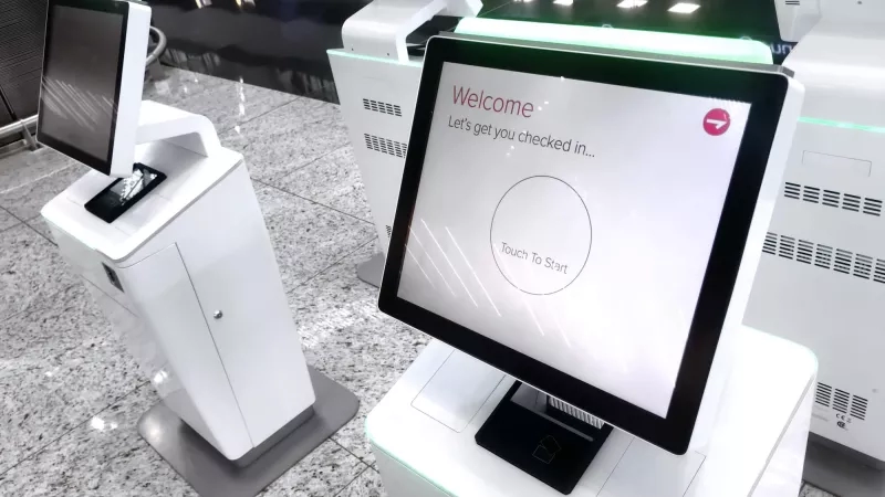 An interactive hotel kiosk for digital check-in, with a welcoming message and a "Touch to Start" prompt.