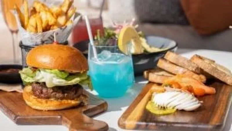 A table with a burger, fries, and a blue drink on it.