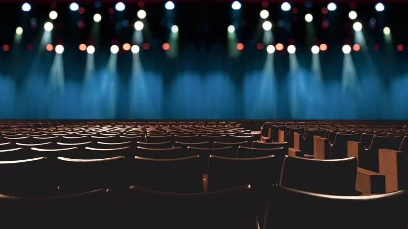 Empty vintage moving theater venue type with stage, chairs, and spotlights creating an elegant ambiance.