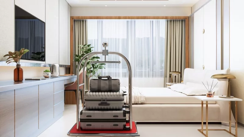 A luxurious hotel room with large windows, plants, and TV, with luggage on a trolley.