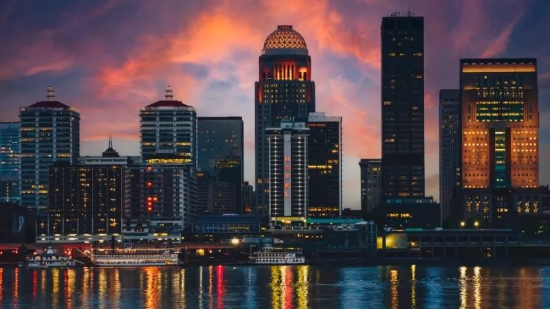 Louisville's skyline glows at dusk, with Galt House's iconic dome and vibrant waterfront scene.