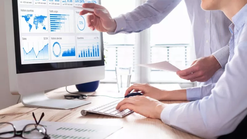 Two people are analyzing web traffic on a computer screen, working together in an office setting.
