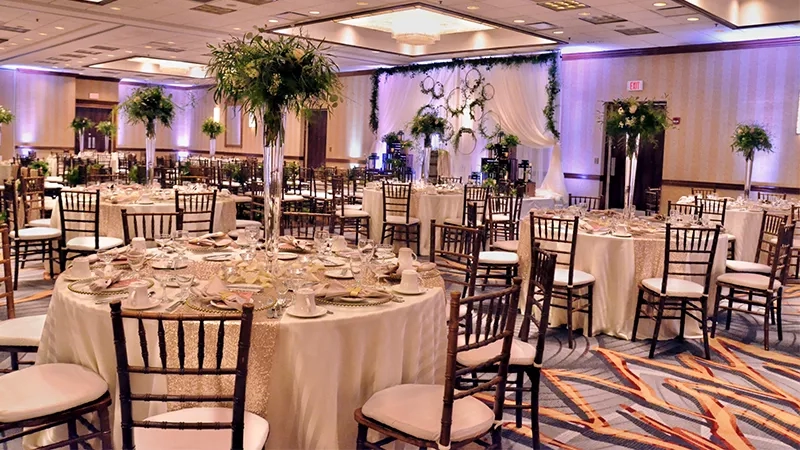 A round dining table with chairs, white tablecloth, and flower vase at DoubleTree by Hilton Hotel Newark Airport.