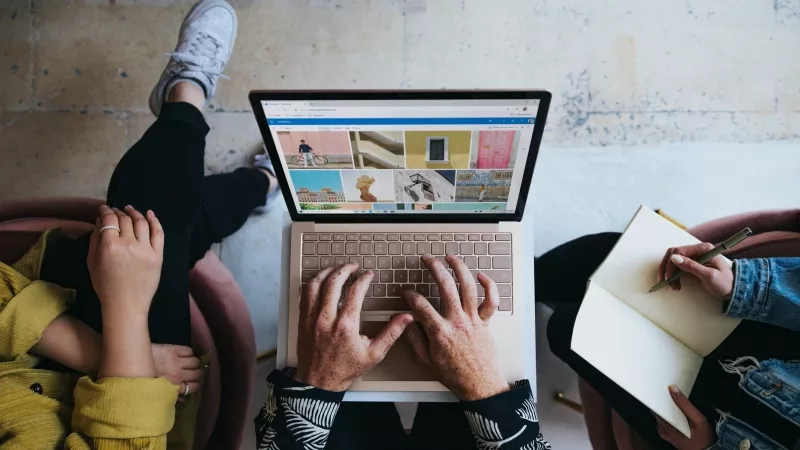 Three people sitting on a couch using a laptop to plan an event.