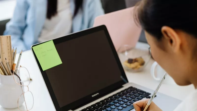 Two women working in an office with post-it notes and a laptop on the table.