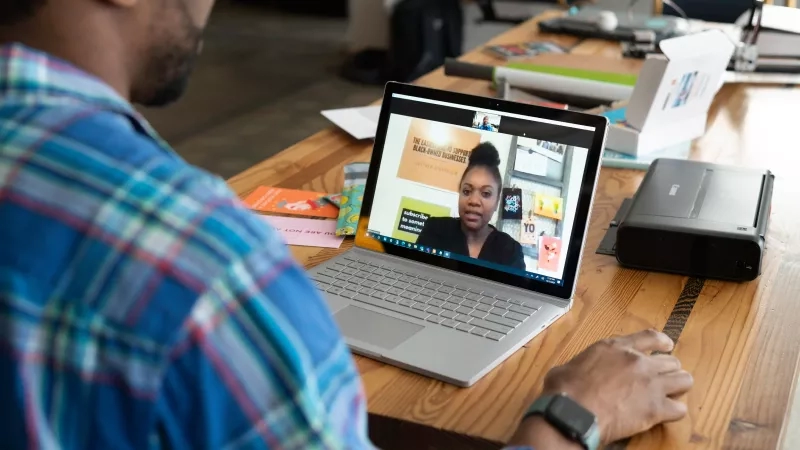 Man on laptop having a virtual meeting with a woman on the screen.