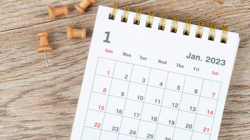 Calendar with thumb tacks on a table for January 2023, a reminder of tax season.