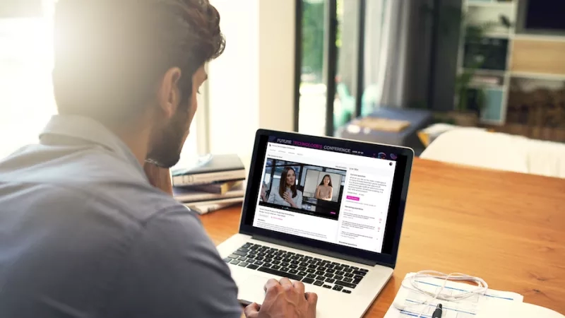 Man watching a video call on his laptop at the office, showing the Future Technologies Conference.
