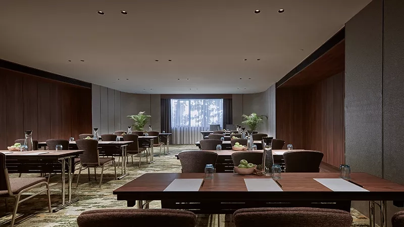 Rafflesia meeting room, tables with chairs, white papers, and glass of water, plants, and a large window.