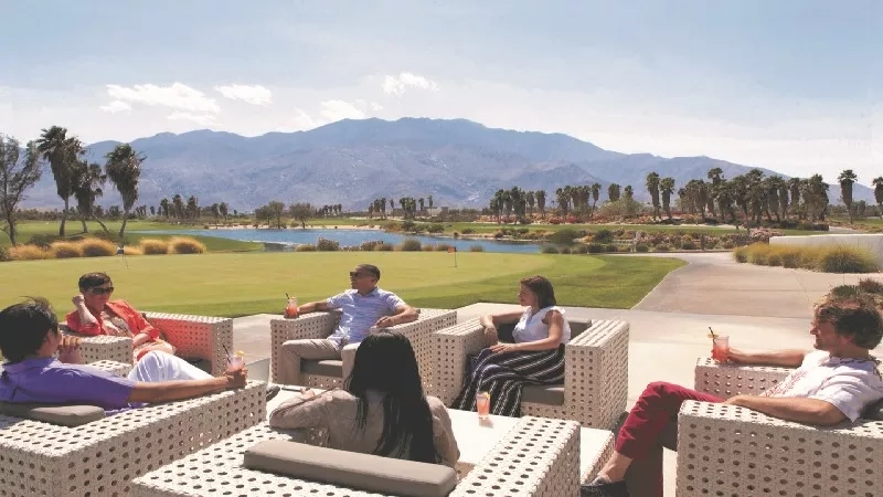 People enjoy cocktails at The Resort at Paws Up overlooking the golf course and mountains.