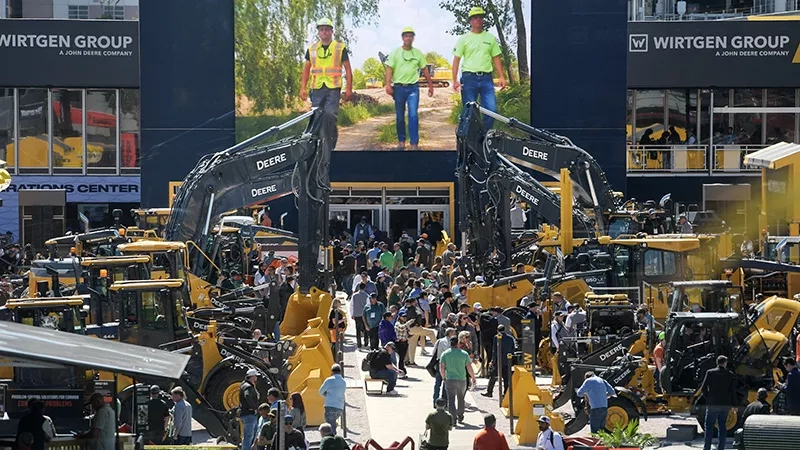 A large group of people is standing in front of a big screen at a construction site.