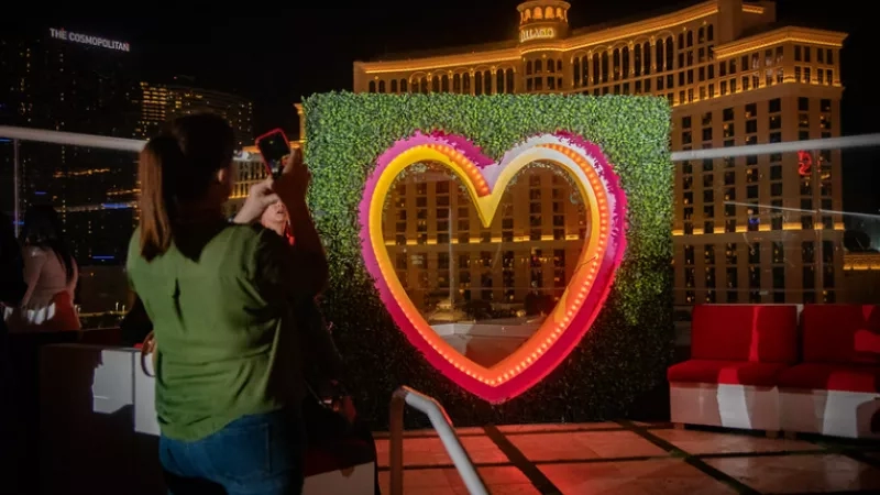 A woman taking a picture of a heart-shaped structure in front of the Bellagio Hotel in Las Vegas.