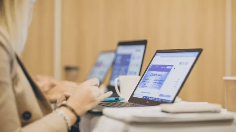 Woman at a meeting with a laptop open to an event page.