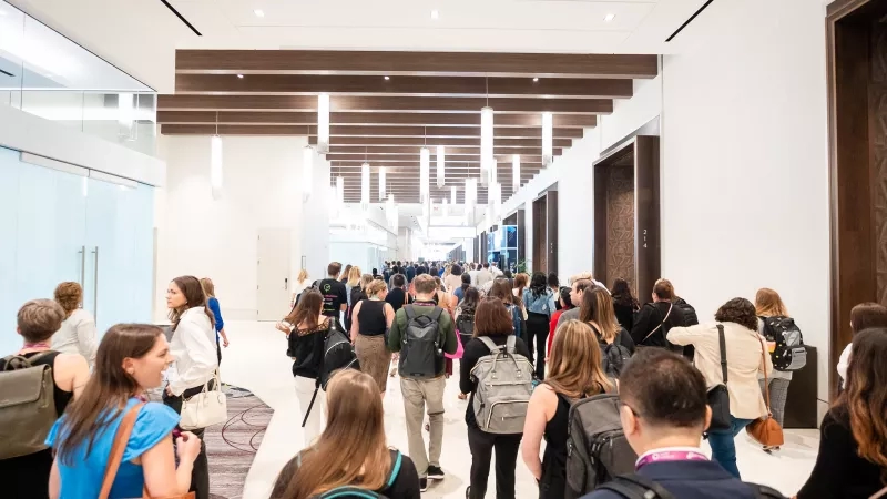 Large crowd of business people walking down the hallway of a convention center.