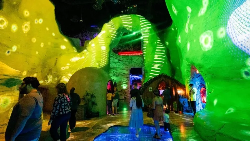 People are visiting the aquarium, where they are exploring the sea in a dark room with neon lights.