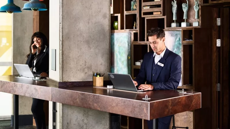 Man and woman work at a hotel front desk in a modern space.