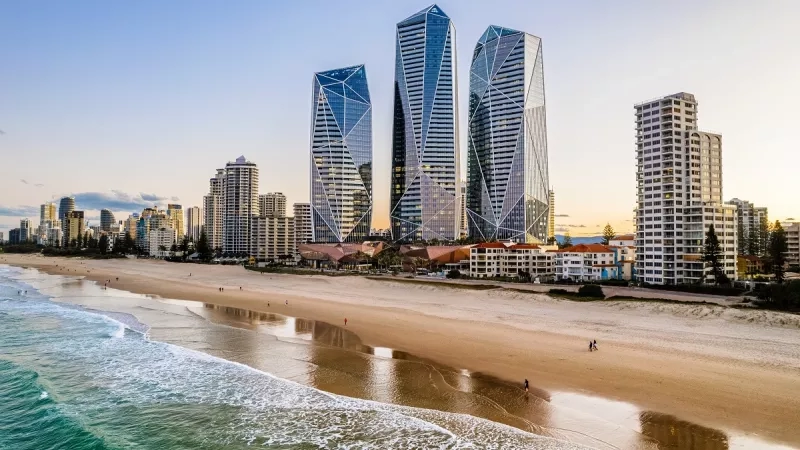 Langham Gold Coast absolute beachfront view of ocean and three hotel towers with guests walking on the beach