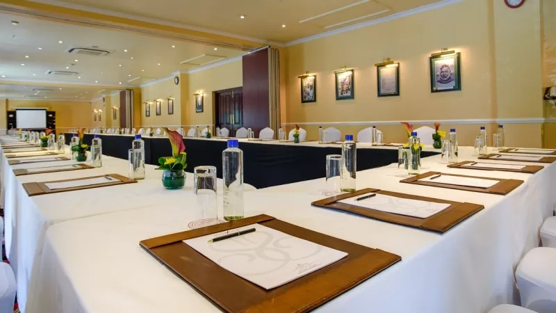 Sarova Stanley Nairobi - The Hemingway conference room with long tables and chairs, framed pictures, and flowers.