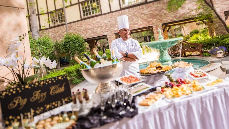 A chef standing next to a banquet table in front of a fountain at the Mission Inn Resort & Club.