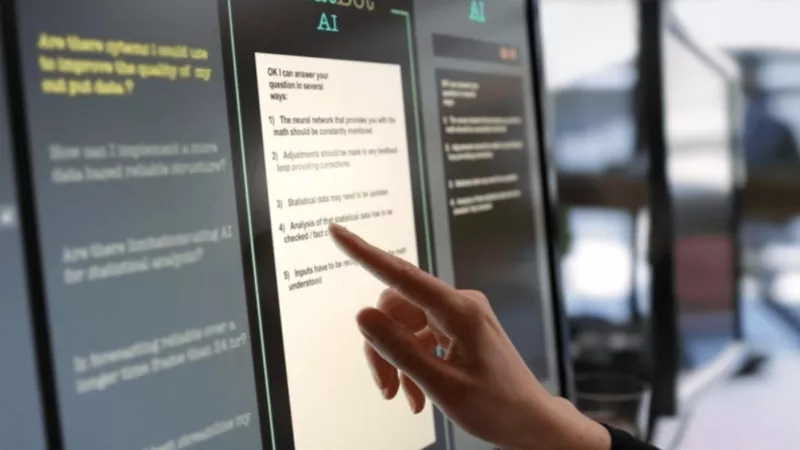 A person pointing at a monitor with a list of answers provided by an AI system.