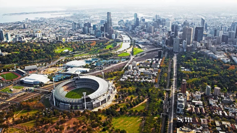 Aerial view of the city and the stadium with a river and trees on a cloudy day.