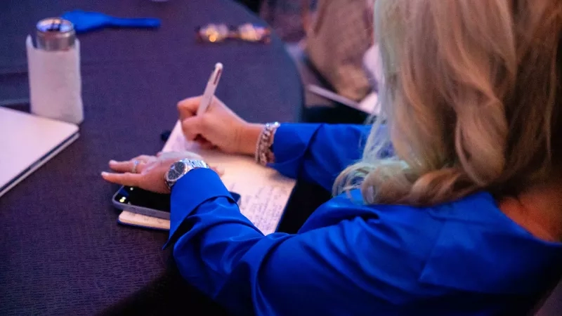 A woman writing in a notebook at Cvent CONNECT 2023 in National Harbor, Maryland.