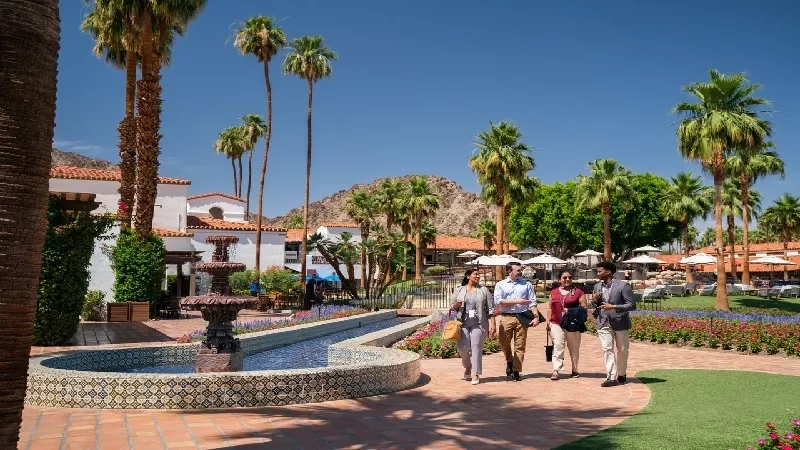 A group of four people walk near a fountain at the Spa Resort Casino.