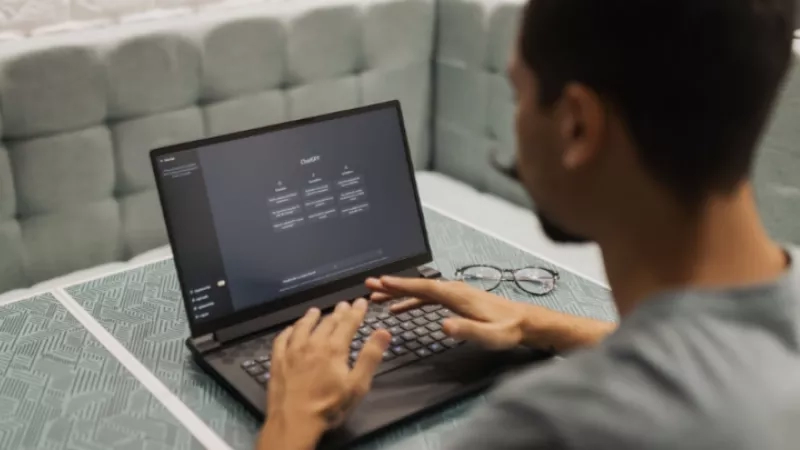 Man using a laptop to type on chat gbt in a coffee shop.