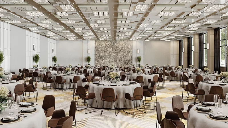 A hotel's large dining area with tables, chairs, and an intricate wall design, set against a bright background.