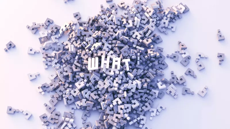 Several alphabets are randomly placed on a white surface, with the text "WHAT" in the center.