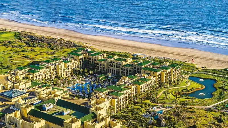 Aerial view of a resort with a beach, ocean, and pools.