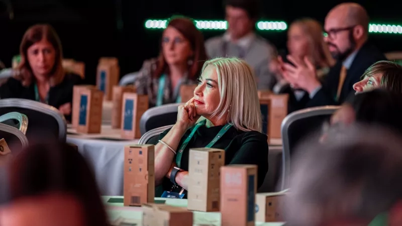 Group of people listening to a speaker at a corporate event with a person clapping their hands.
