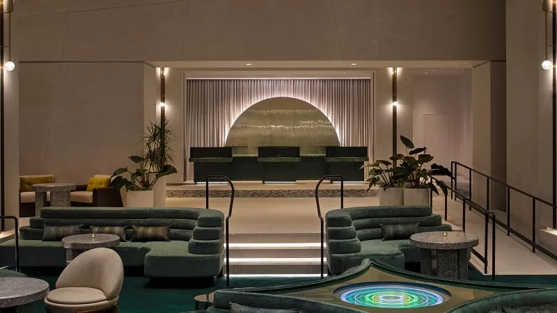 Lobby of the Pendry San Diego hotel with a green rug and a large moon-shaped window.