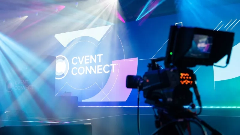 Livestreaming setup with a camera and screen displaying the text "Cvent Connect" in an indoor event space.
