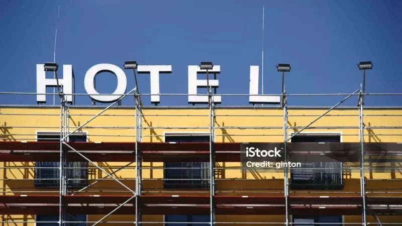 The top of a hotel under construction, with a blue sky and yellow building stock photo.