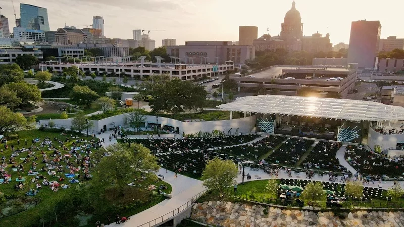 Moody Amphitheater in Austin, Texas, with an aerial view of cityscape, greenery, and a sunset ambiance.