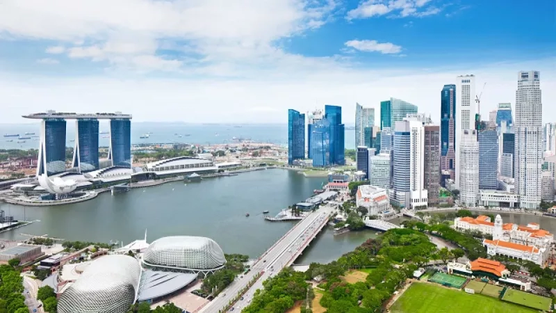 Top view of Marina Bay Sands, Singapore, with tall buildings, a river, and a green field.