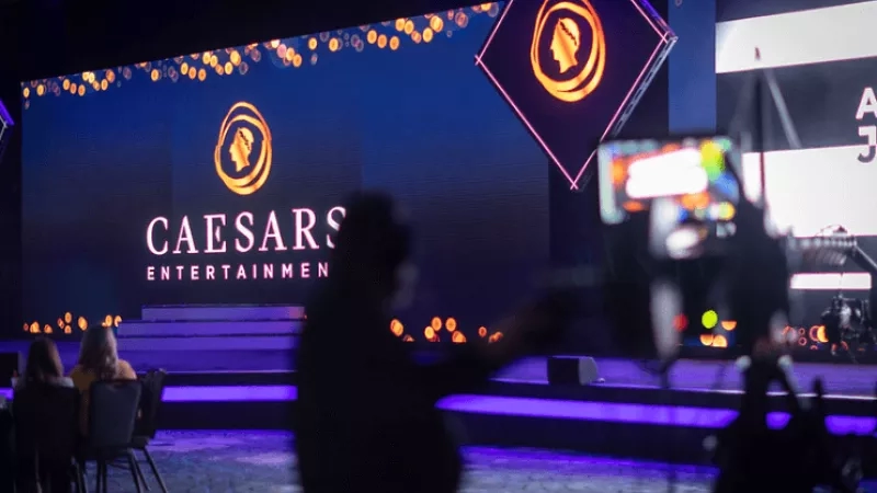 Caesars Entertainment event is happening on stage with a large screen and a camera filming the event.