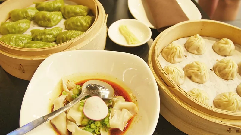 A bowl of soup dumplings from Din Tai Fung Restaurant Tukwila is served on a table.