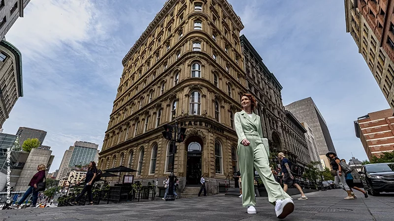 Woman in green suit walking in front of St. Sulpice in Montreal.