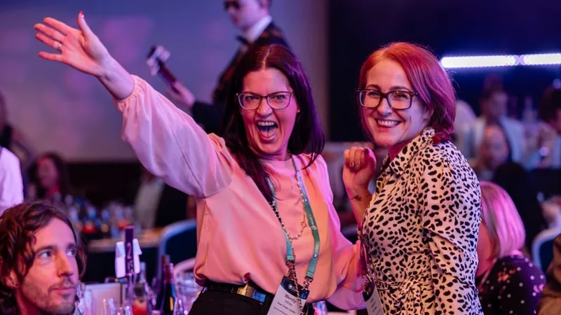Two women smiling at the 2024 National Hospital Awards with their arms raised in the air.