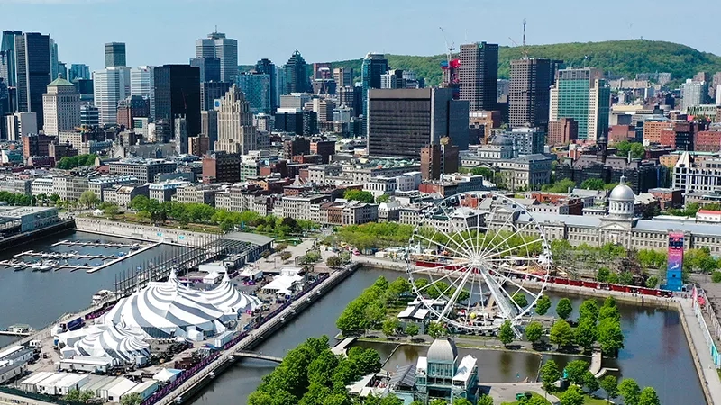A city with many buildings, a Ferris wheel, and a river, likely Montreal, Quebec, Canada.