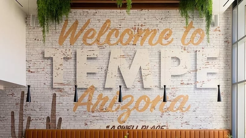 Tempe Arizona Welcome sign with brick wall, plants, and hanging lights.